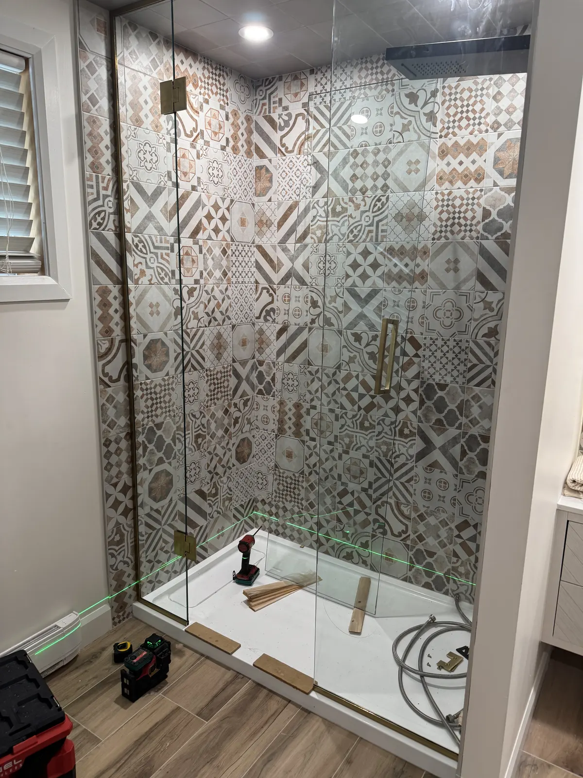 Douche en verre avec cadre doré et carrelage à motifs