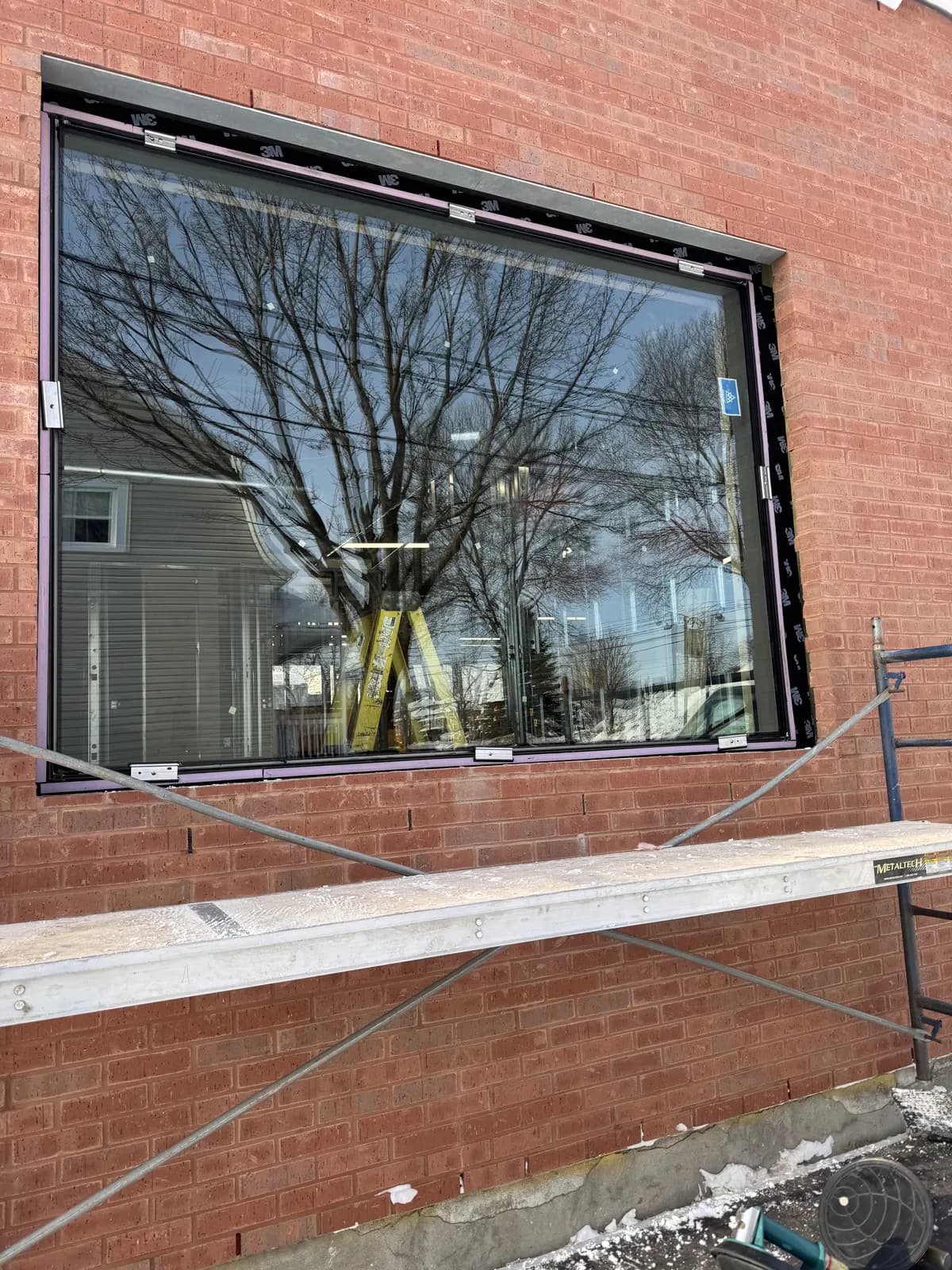 Grande fenêtre commerciale posée sur mur de brique