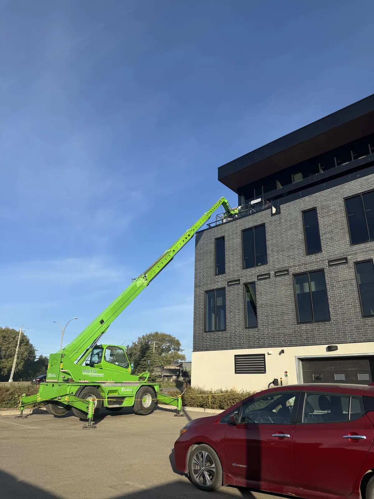 Grue télescopique installant un mur-rideau commercial